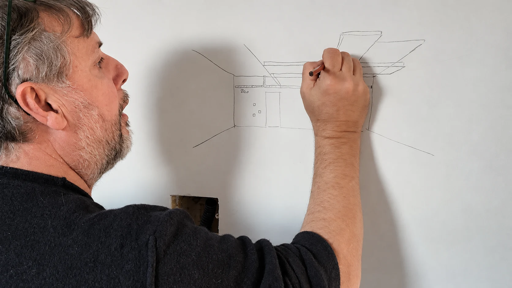 Giulio Fenyves disegna sulla parete di cantiere le geometrie del controsoffitto dell'attico a Milano